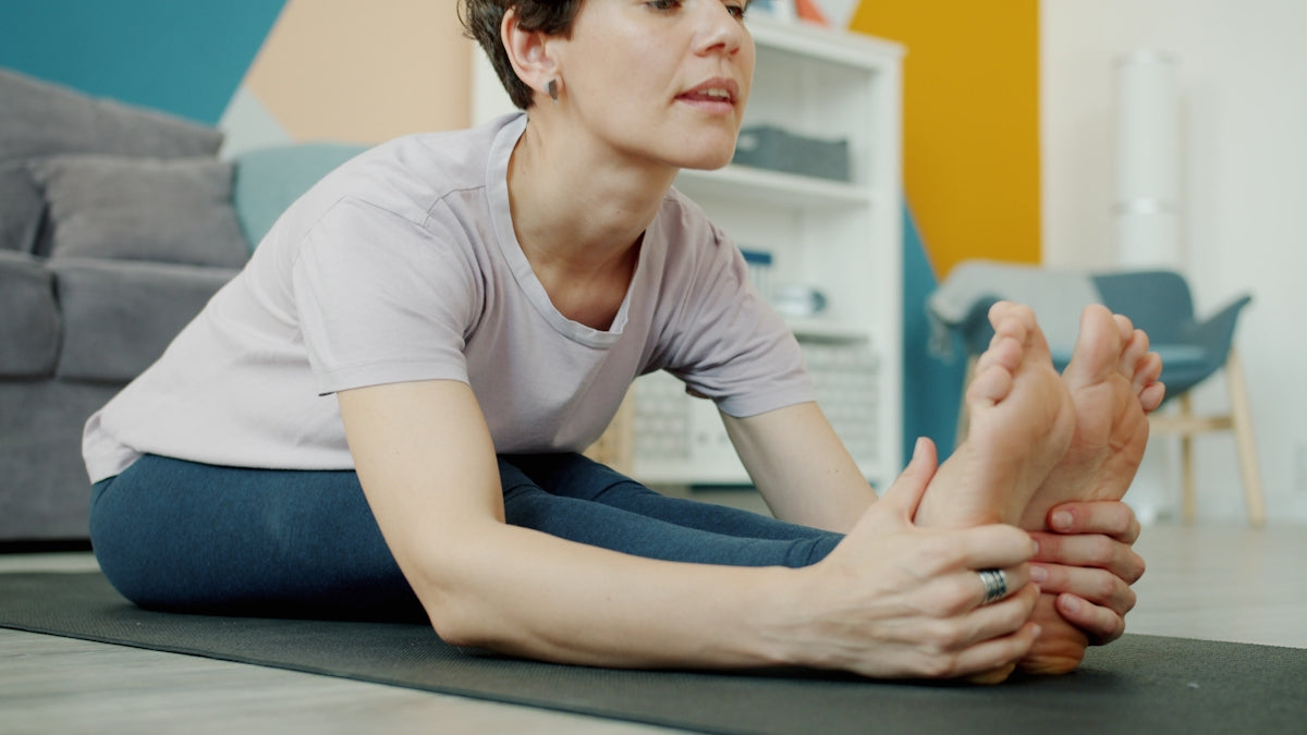 Woman stretching her legs on a yoga mat.
