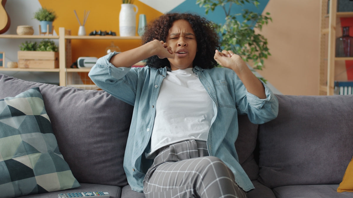 Woman sitting on couch with hands near face.