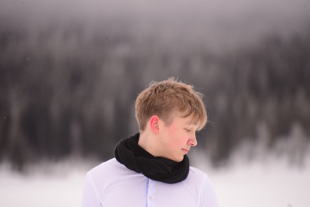 a man with a scarf around his neck standing in the snow